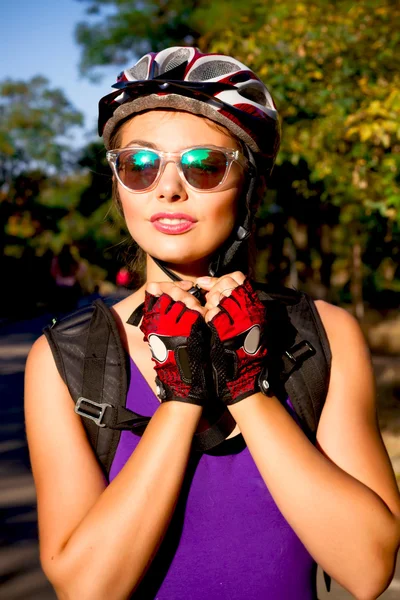 Young woman on the bicycle wearing on the helmet.Bike helmet - woman putting biking helmet on outside during bicycle ride.Woman wearing biking helmet. Close-up portrait of female cyclist.