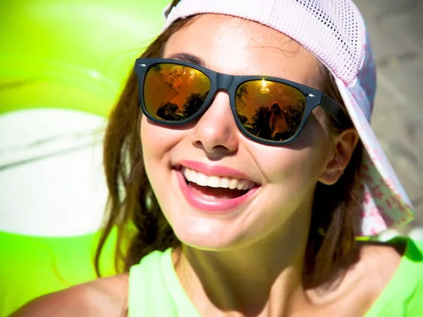 Close up summer portrait of a young girl hipster beautiful brunette teenage girl in sunglasses having fun at pool party.Happy summer vacation girl. Beautiful caucasian woman having fun and smiling