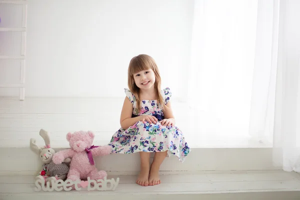 Little girl sitting next to toys