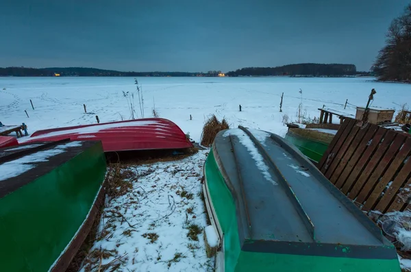 Fisherman boats on frozen lake shore. Winter landscape