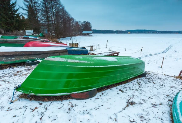 Fisherman boats on frozen lake shore. Winter landscape