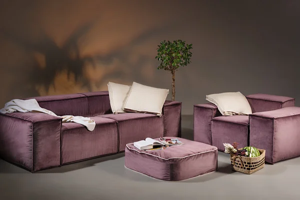 Purple sofa with armchair, table, pillows and blanket