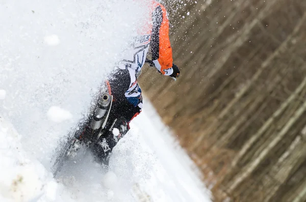 Back view of motocross rider on motorbike in deep snow