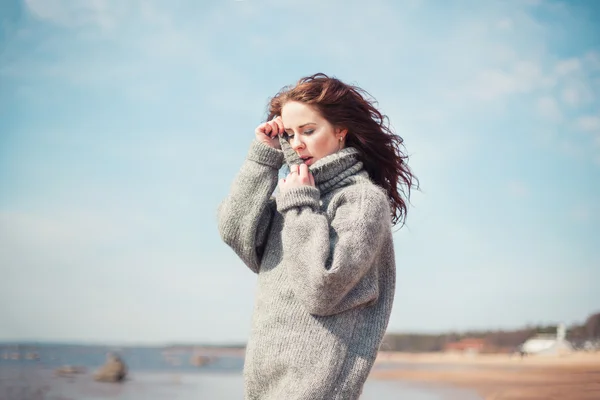 Attractive woman wearing a warm cardigan at the cold beach