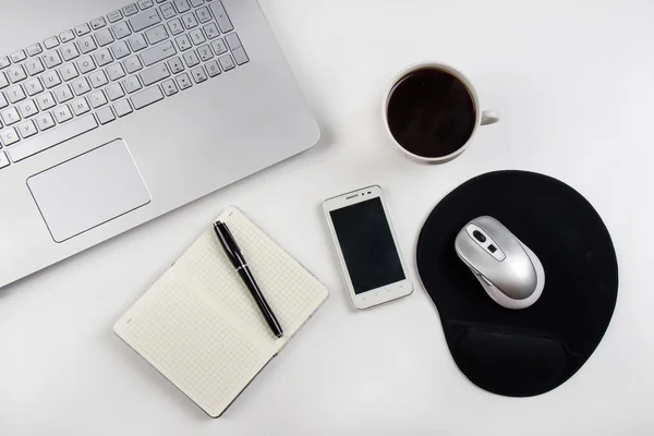 Cup of coffee and laptop on white table.