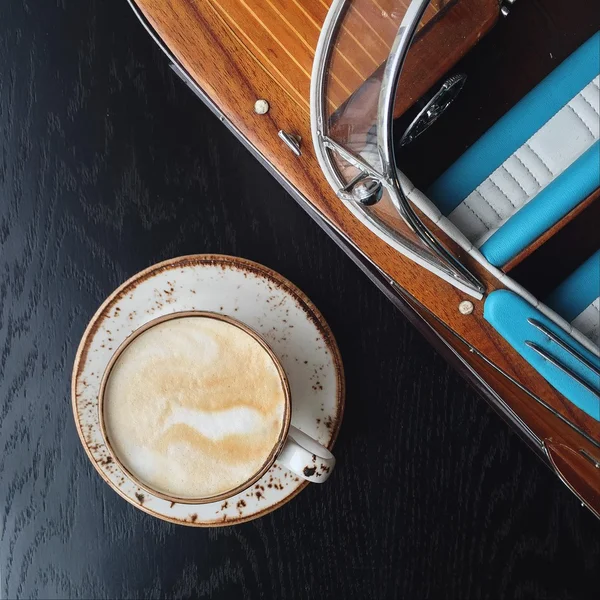 Cup of coffee and model of wooden boat