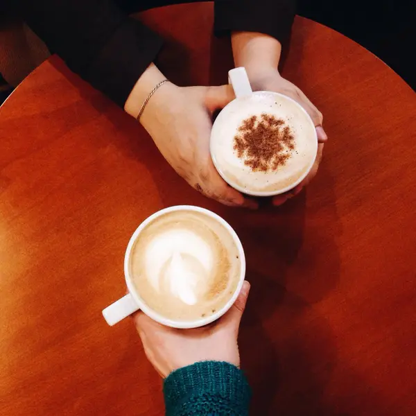 Cups of coffee in hands of couple