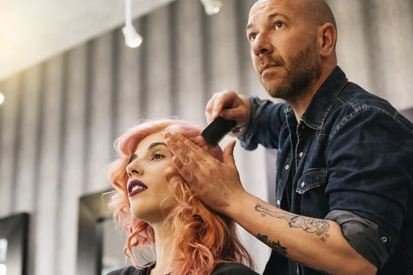 Beautiful woman getting haircut by hairdresser.