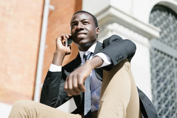 African man smiling when he is using his mobile.