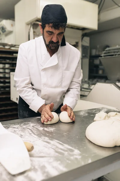 Baker kneading dough in a bakery.