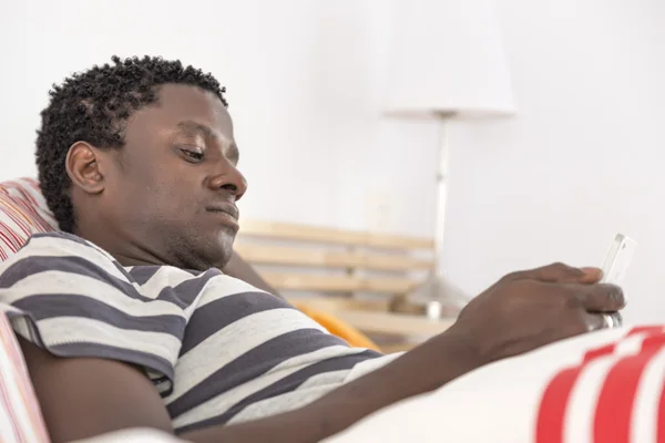 African american man with his phone in bed