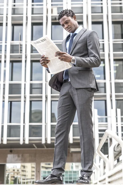 Black businessman reading newspaper outdoor