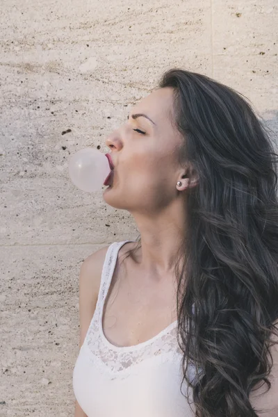 Beauty young woman makes a balloon with a bubble gum