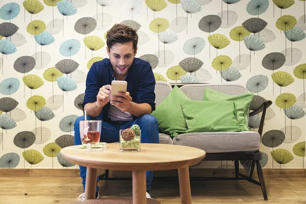 Bar smart casual young man writing message on smartphone.