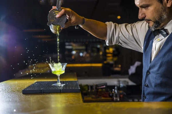 Barman is making cocktail at night club