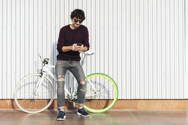 Handsome young man with mobile phone and fixed gear bicycle.