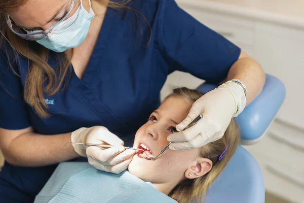 Dentists with a patient during a dental intervention to girl.