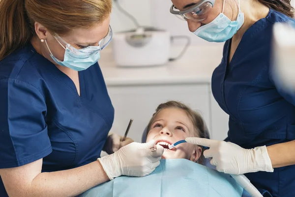 Dentists with a patient during a dental intervention to girl.