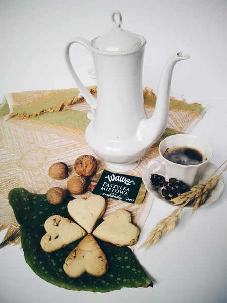 Teapot, cookies, walnuts and cup of coffee