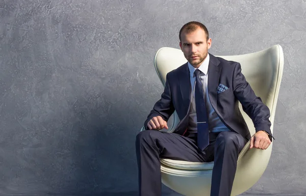 Brutal businessmen in suit with tie sitting on chair. Boss concept.
