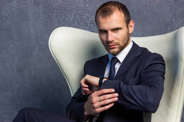 Brutal businessmen in suit with tie sitting on chair. Boss concept.
