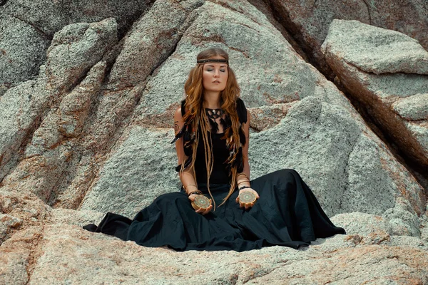 Young beautiful woman with tarot cards in her hands with stone b