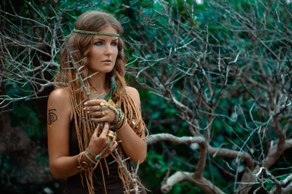 Beautiful young woman holding branch with thorns in her hands