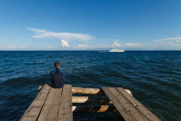 Man sitting on old wooden dock with Baikal lake view