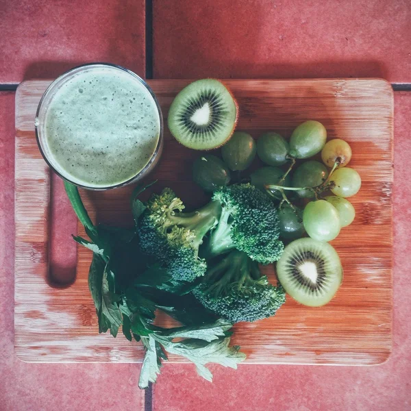 Smoothie, green fruit and vegetables on cutting board