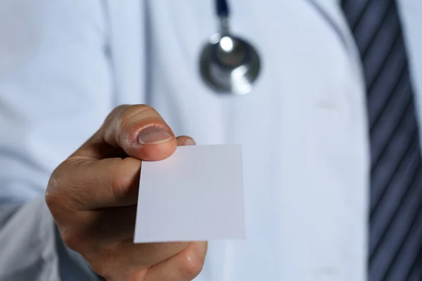 Male physician hand holding and giving white blank calling card