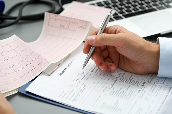 Male doctor hands with cardiogram chart on clipboard pad