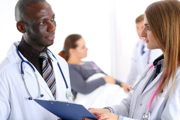Two doctors share and discuss important document on clipboard pa