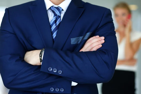 Hands of male businessman in blue suit crossed on chest
