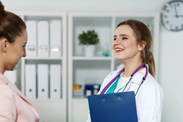 Doctor holding medical history while chatting with patient