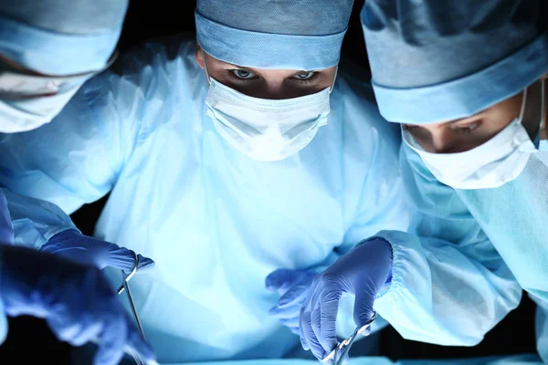 Group of surgeons at work operating in surgical theatre