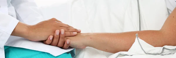 Friendly female doctor hands holding patient hand