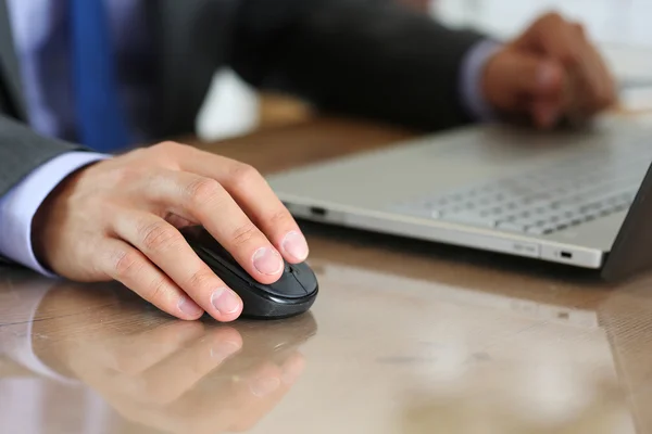 Hands of businessman in suit holding computer wireless mouse