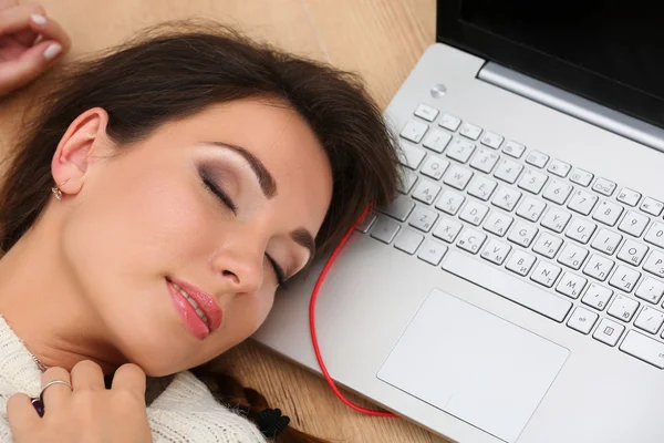 Beautiful woman lying on laptop computer on wooden floor sleepin