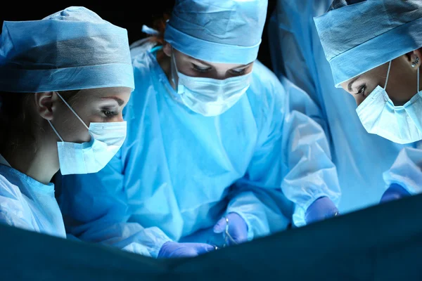 Group of surgeons at work operating in surgical theatre