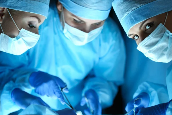 Three surgeons at work operating in surgical theatre