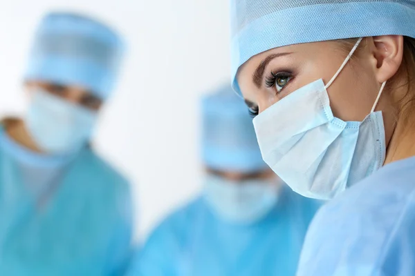 Three surgeons at work operating in surgical theatre saving pati