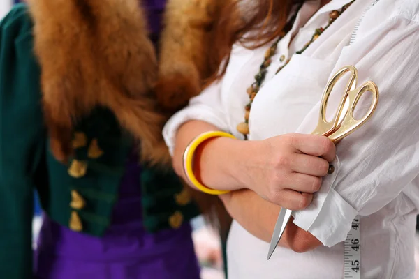 Female fashion designer holding big golden tailor scissors in ha
