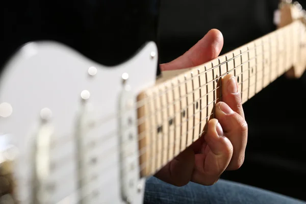 Male hands playing electric guitar on maple fretboard