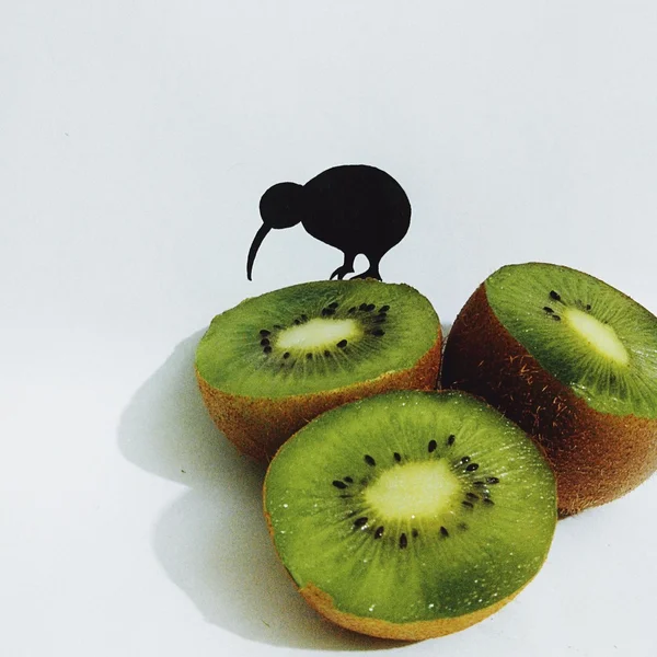 Paper kiwi bird on half of kiwi fruit