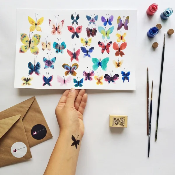 Watercolor butterflies on paper in hand