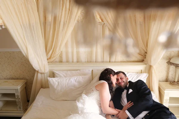 Bride and groom embracing in hotel room bed