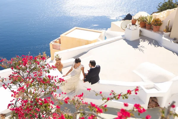 Bride and groom sitting on the roof of a house in Santorini