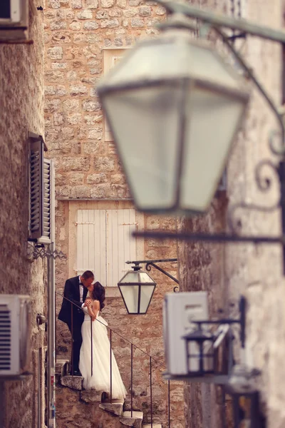 Bride and groom kissing on stairs in old city