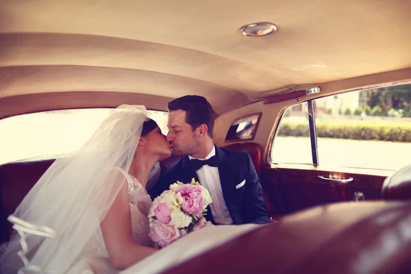 Bride and groom kissing in a retro car