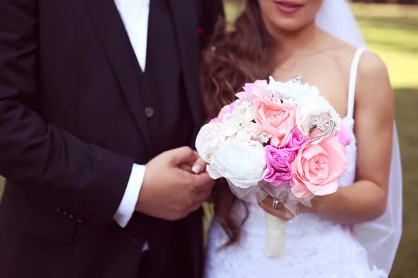 Bride and groom holding hands. Bride holding wedding paper flower bouquet